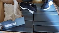 Eight black New Balance 327 sneaker boxes stacked, two pairs open on top