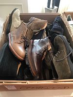 Box containing multiple pairs of boots and shoes in leather and suede