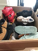 Box with multiple pairs of sneakers showing red, black, grey/white, tan and mint shoes