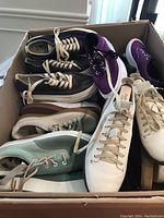 Box containing assorted shoes in sizes 7-8 US and 40-41 EU from multiple brands, showing variety of colors and styles including purple, black, gray, and mint green casual sneakers.