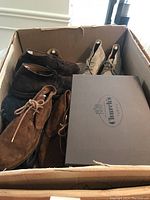 Four pairs of suede chukka boots in a cardboard box with a Church’s shoebox visible