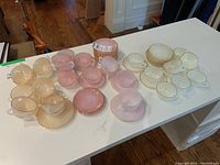 Three group arrangement of ivory cups on saucers (left), pastel pink cups on saucers (center), ivory cups on saucers (right) displayed on white table