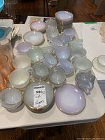 Overhead view of stacks of pastel opalescent glass saucers and scattered matching cups with gold rims