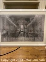 Front view of the framed artwork leaning against shelving on hardwood floor