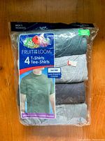 Clear view of Fruit of the Loom 4-pack men's T-shirt package featuring assorted colors and tag-free design in new condition, size small.