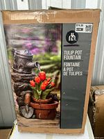 Box showing HomeRoots Tulip Pot Garden Fountain with red tulips, watering can, and garden trowel design. Box price sticker is visible.