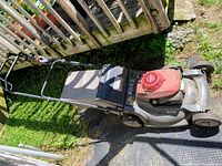 Top side view of the Honda lawn mower showing red engine cover, grass catcher, and metal deck.
