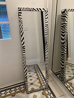 Full-length mirror with zebra print frame showing the front of the jewelry armoire.