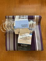 Close-up of packaged curtain set including 13 clear plastic hooks attached to curtain