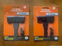 Two new black metal tee hinges each 4 inches with screws in original orange packaging from Fix It! brand
