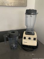 Vitamix blender base with one container attached and second container next to it