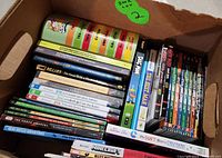 Box filled with kids books and collections featuring various titles including Dog Man and Minecraft guides.