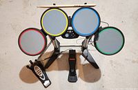 Top view of the electronic drum kit showing four color-coded drum pads and two foot pedals (single and double bass).