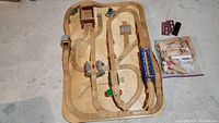 Top-down view of wooden train track platform with arranged tracks, bridges, tunnels, and small Thomas themed elements.