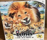 Box showing a colorful 3D puzzle of a lion family with a male lion and three cubs, butterflies, and birds in the background, labeled Prime 3D puzzle by HONS with 48 pieces.