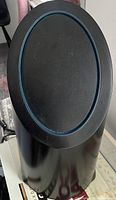 Photo showing black air purifier with oval top and blue trim