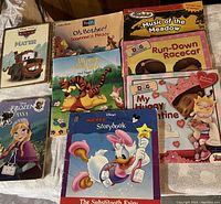Photo showing 8 assorted Disney-themed children’s books including Cars (Mater), Pooh, Winnie the Pooh, Doc McStuffins, Frozen Anna, and Mickey/Daisy Duck storybooks in good condition.