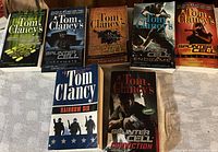 Photo showing seven Tom Clancy books including titles from Splinter Cell series and Rainbow Six.