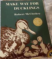 Front cover of 'Make Way for Ducklings' showing the illustration of a mother duck and ducklings with title and author name, including a gold award medal.