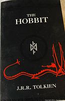 Front cover of The Hobbit by J.R.R. Tolkien with dragon illustration and rune symbol