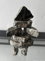Front view of signed stone Inukshuk sculpture showing stacked stones with natural texture and angular shapes.
