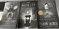 Three paperback books of the Miss Peregrine's Peculiar Children series arranged flat showing front covers