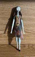 Front view of Sally figurine standing on a wooden surface showing full figure and dress details