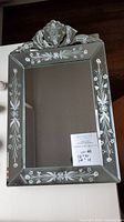Front view of the antique etched mirror showing etched floral design around the edges and decorative top crest.