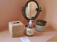 Photo showing the oval standing mirror with metal Art Nouveau frame, woven tissue box cover, hand soap bottle, and ceramic jar.