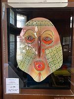 Full view of ceramic face mask in plexiglass case, showing entire artwork and case dimensions.