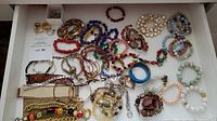 Overview of assorted bracelets, rings, and earrings arranged on white surface
