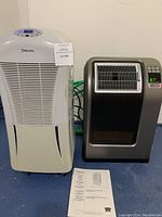 Both appliances side by side: white Danby dehumidifier with digital control panel and gray Lasco ceramic heater showing temperature 67°.