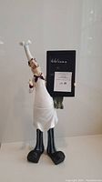 Front view of large French chef figurine holding vertical chalkboard with welcome message