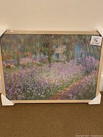 Full view of the framed print with visible artwork, wooden frame, and protective plastic wrapping around it.