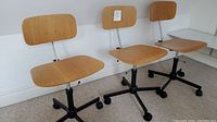 Front view of three plywood desk chairs in a row showing seats and backs