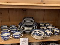 Shelf view of two clusters of six tea cups and stacked plates