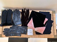 Full display of five items on basket surface: three pairs of gloves arranged side by side and two scarves folded beneath them.