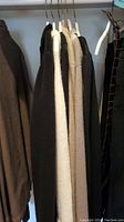 Photo of multiple hanging cardigans in closet including black and white colors.