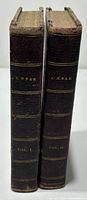 Spines of two leather bound books with gilt lettering 'Cesar' and volume numbers showing wear.