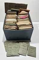 Blue cardboard box with assorted envelopes of postcards and several Jubilee Stores London postcard sets in front