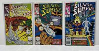 Three Silver Surfer comics in protective sleeves: #8, #34, and #35 showing cover art with Silver Surfer and Thanos.