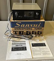 Full setup showing tuner atop original box with manuals and cables laid out in front.