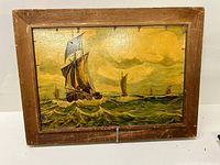 Full frontal view of the oil painting of a close-up sailing ship on the sea in an aged wooden frame