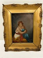 Full view of the framed antique painting showing a woman holding a child, highlighting the ornate gold frame.