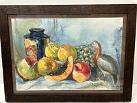 Full view of the framed watercolor painting showing the still life arrangement of fruits, ceramic jar, and bird figurine with signature D.K. Raje and date.
