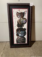 Framed colorful painting of an African woman carrying a baby, in abstract style, hung on wall.