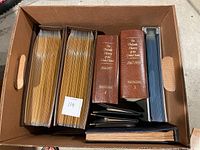 Box containing several binders, albums, and volumes of postage stamps and stamp history books.