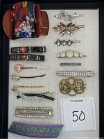 Photo showing a collection of various hair clips, barrettes, and hair combs organized neatly. The accessories feature rhinestone decorations, metal finishes, and floral patterns.