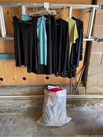 Hanging assorted women's tops, skirts, and pants in various colors including black, light blue, yellow, navy, and patterned navy with white dots