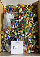 A box full of assorted small and medium marbles with multiple color swirls and opaque cores.
